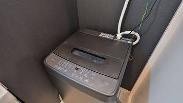 A compact, wall-mounted printer with a control panel and a paper tray, connected to a power outlet.