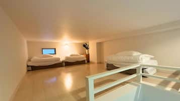 A room with two beds, a television, and a small table with a vase.