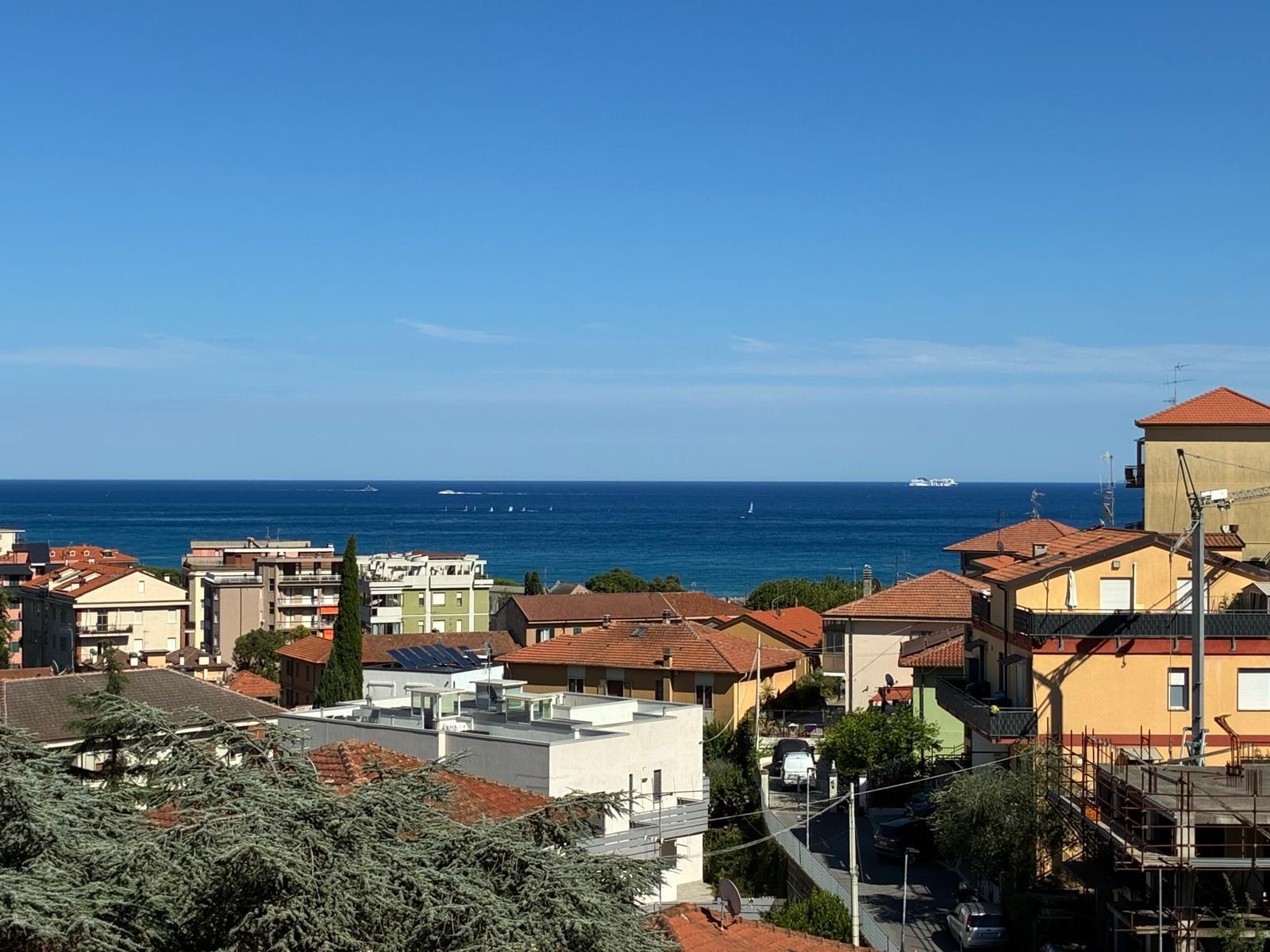 Una zona residenziale sulla costa, con edifici, cielo sereno e il mare sullo sfondo.
