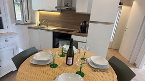 A modern kitchen with white cabinets, a wooden countertop, and a dining area with a yellow patterned tablecloth. - Villa Mary - Two Bedroom Apartment, Sleeps 4 (Marina di Andora)
