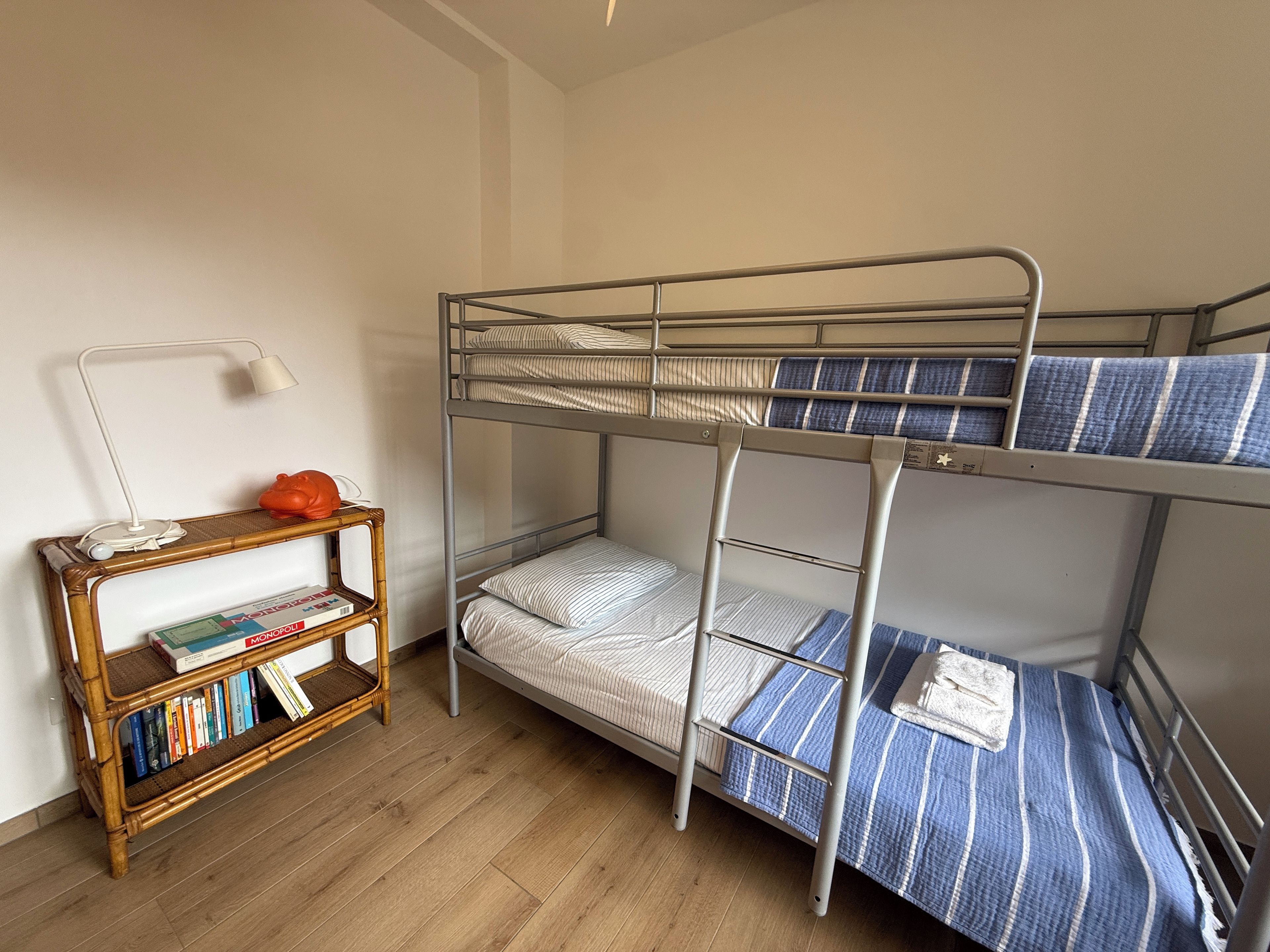 Uma cama beliche com uma cama inferior e uma escrivaninha com livros e uma luminária.
