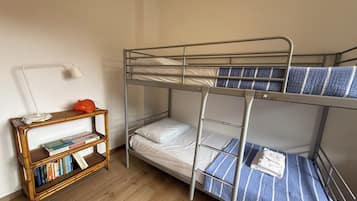 A bunk bed with a lower bunk and a desk with books and a lamp.