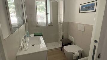 A compact bathroom with a shower, toilet, and sink.