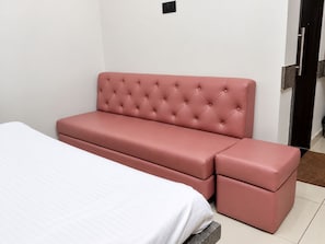 Une pièce avec un lit, un canapé rose et un banc.
