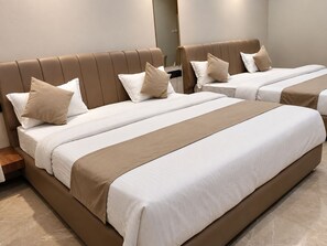 Quarto de hotel com duas camas, cada uma com cabeceira, e uma mesa de cabeceira entre elas.