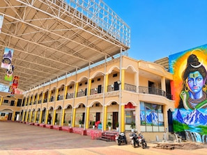 A multi-story building with a covered central area, a mural on the right, and a row of parked motorcycles. - Athithi Bhawan (Khandwa)