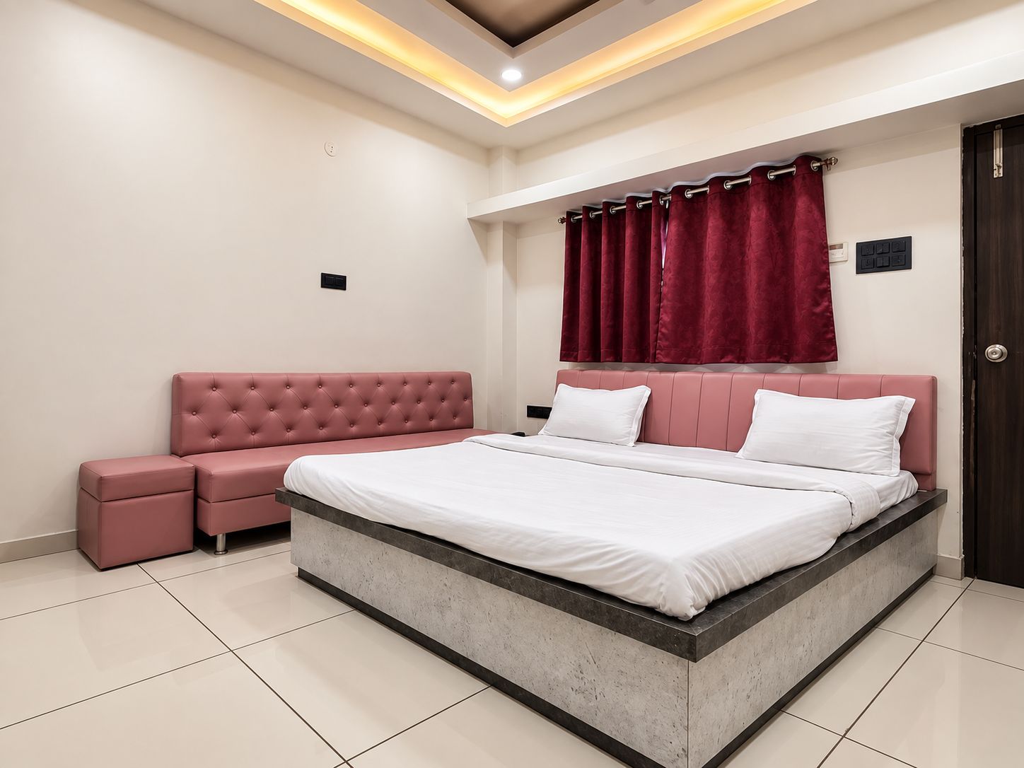 Une chambre moderne avec un grand lit, un canapé rose et un rideau rouge.