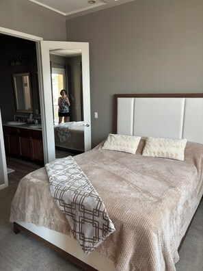 Een slaapkamer met een groot bed, een badkamer met een spiegel en uitzicht op buiten.