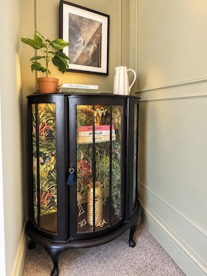 A black cabinet with glass doors, a potted plant, a framed picture, and books on top. - Stylish 4BR Sunderland | Contractor Friendly (Sunderland)