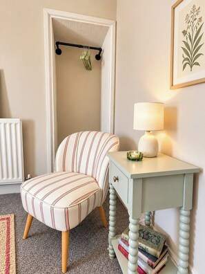 A room with a striped armchair, a small table with a lamp, a radiator, and a framed botanical illustration on the wall. - Stylish 4BR Sunderland | Contractor Friendly (Sunderland)