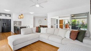 Una sala moderna con sofá modular, una zona de cocina y un comedor.