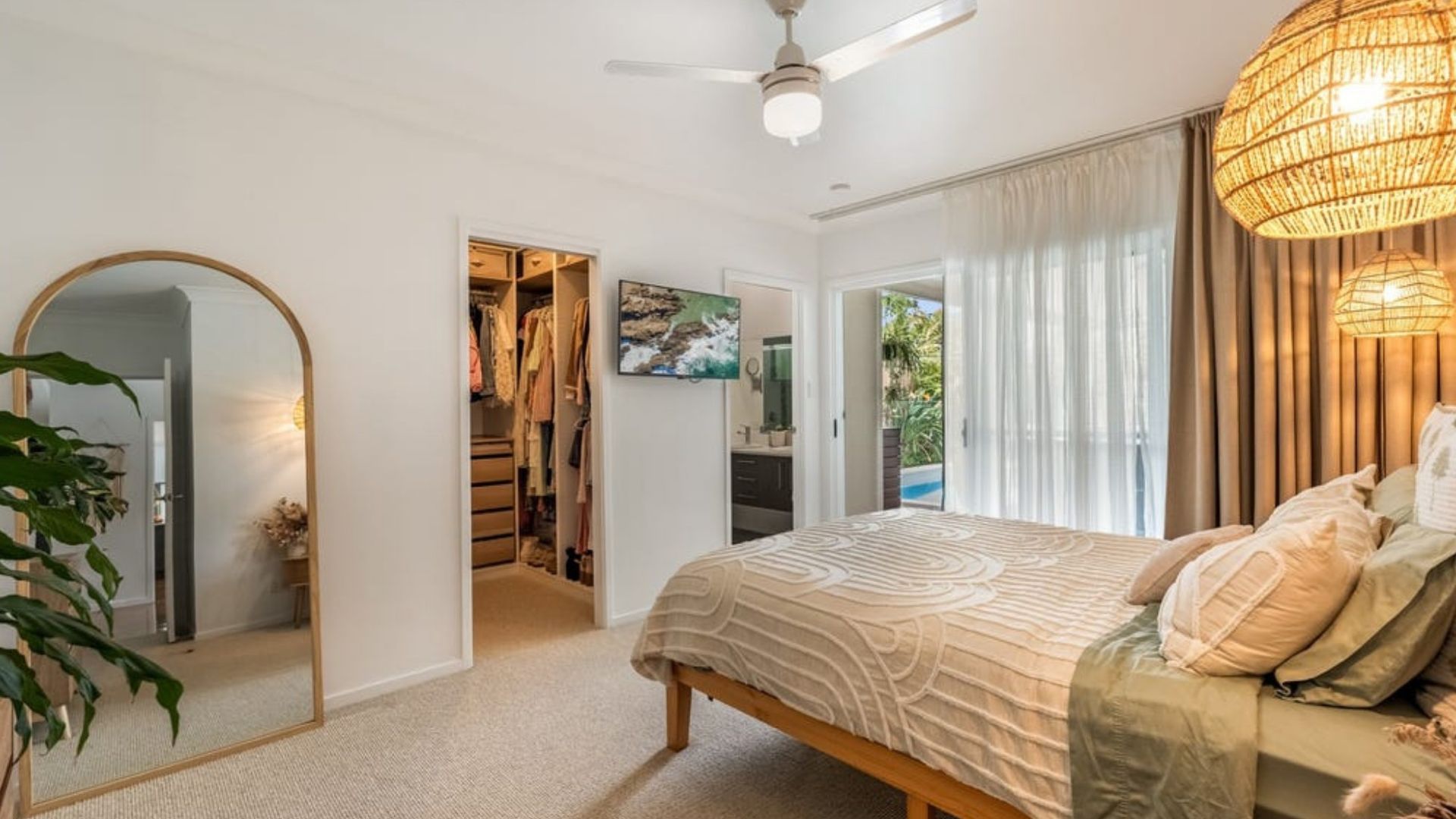 Een slaapkamer met een bed, een plafondventilator, een kledingkast en uitzicht op het omliggende landschap.