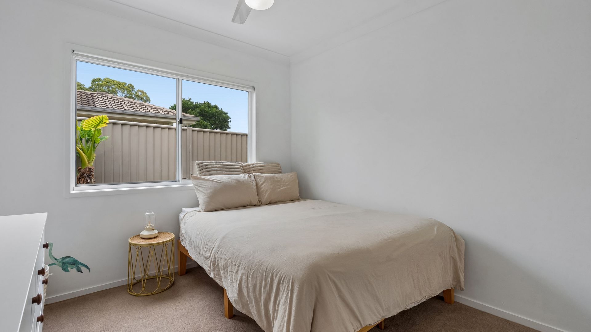 A bedroom with a bed, a bedside table, a lamp, and a window.