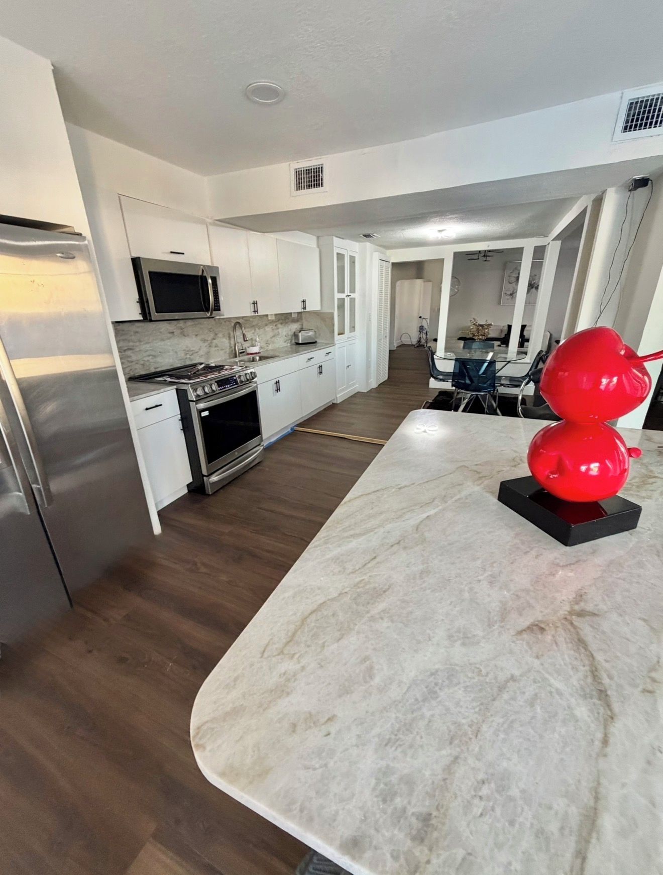 A modern kitchen with white cabinetry, stainless steel appliances, and a marble countertop.
