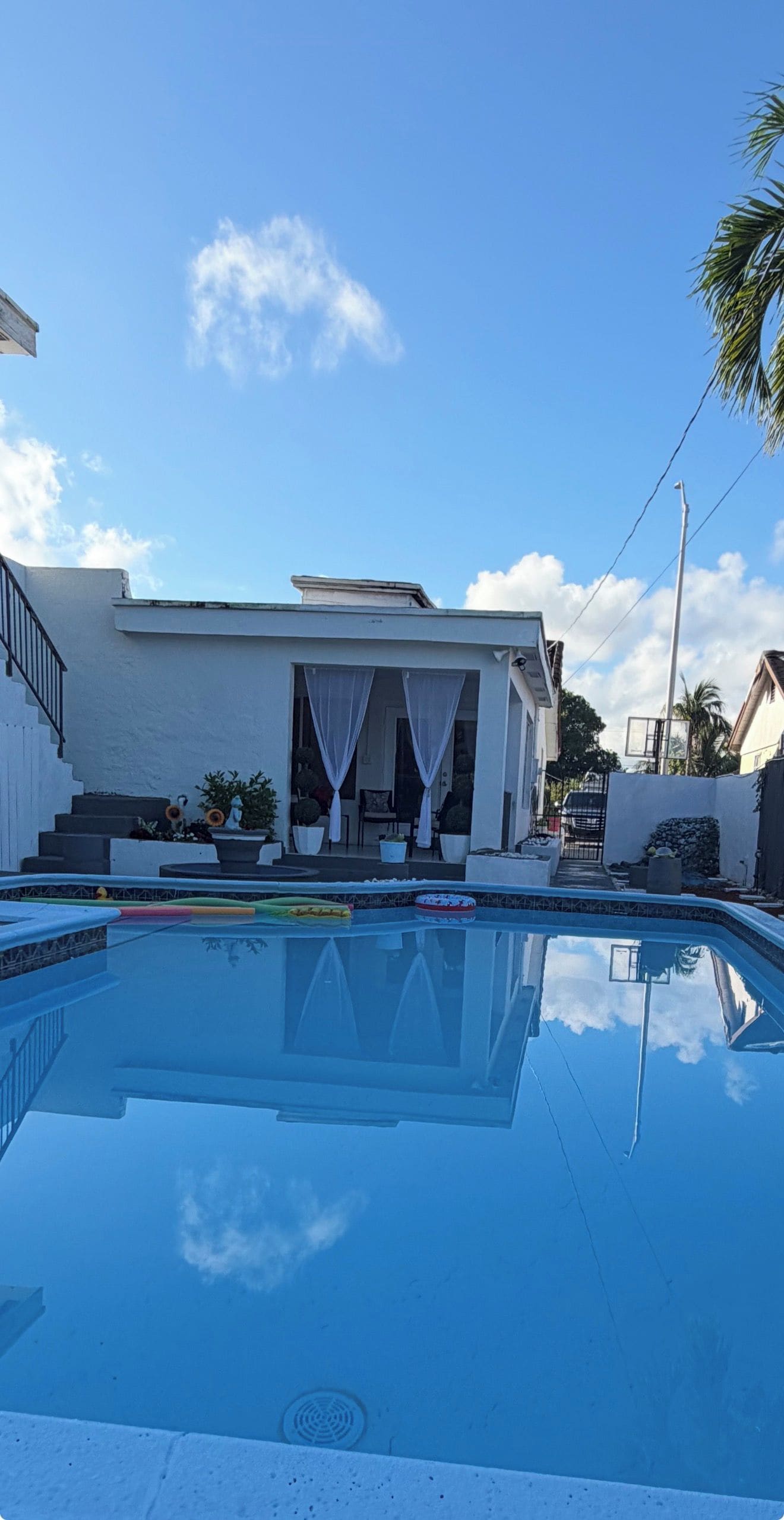 A modern house with a swimming pool, white exterior walls, and a covered outdoor seating area.