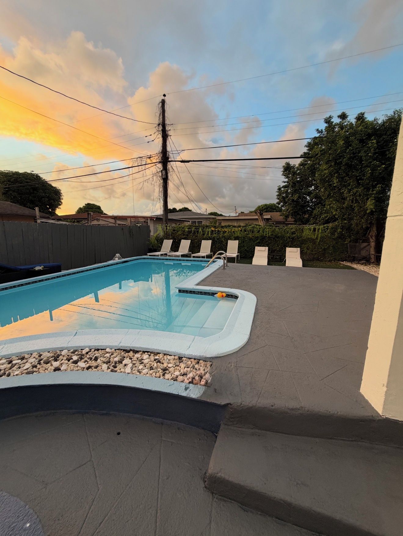 A swimming pool with a tiled deck and lounge chairs.