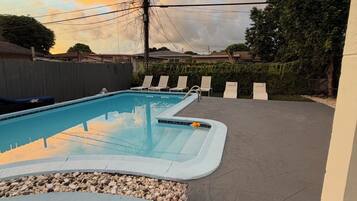 A swimming pool with a tiled deck and lounge chairs.