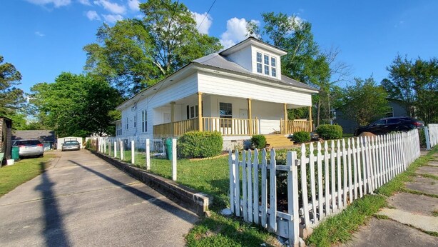 A two-story house with a porch, a garage, and a white picket fence. - 2BR/2BA Furnished Home with Theater room, Wi-Fi & RV Parking (El Dorado)