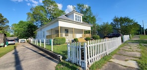 A two-story house with a porch, a garage, and a white picket fence.