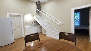 A room with a wooden floor, a white refrigerator, a dining table with two chairs, a staircase with white railings, and a closet with white cabinets. - 2BR/2BA Furnished Home with Theater room, Wi-Fi & RV Parking (El Dorado)
