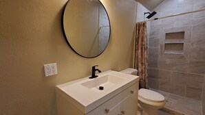 A bathroom with a white sink, a mirror, a toilet, and a shower area. - 2BR/2BA Furnished Home with Theater room, Wi-Fi & RV Parking (El Dorado)