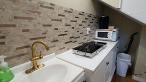 A compact kitchenette with a white countertop, a gas stove, a microwave, and a sink with a gold faucet. - 2BR/2BA Furnished Home with Theater room, Wi-Fi & RV Parking (El Dorado)