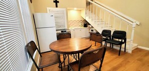A compact kitchen with a refrigerator, stove, microwave, and wooden dining table with chairs.