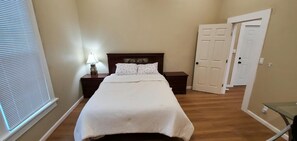 A bedroom with a bed, nightstands, a lamp, and a door.