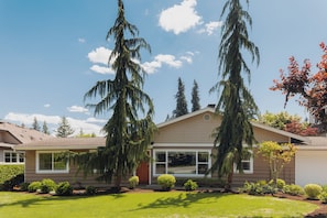 Ein modernes, zweistöckiges Haus mit großem Vorgarten, Garage und gepflegtem Garten.