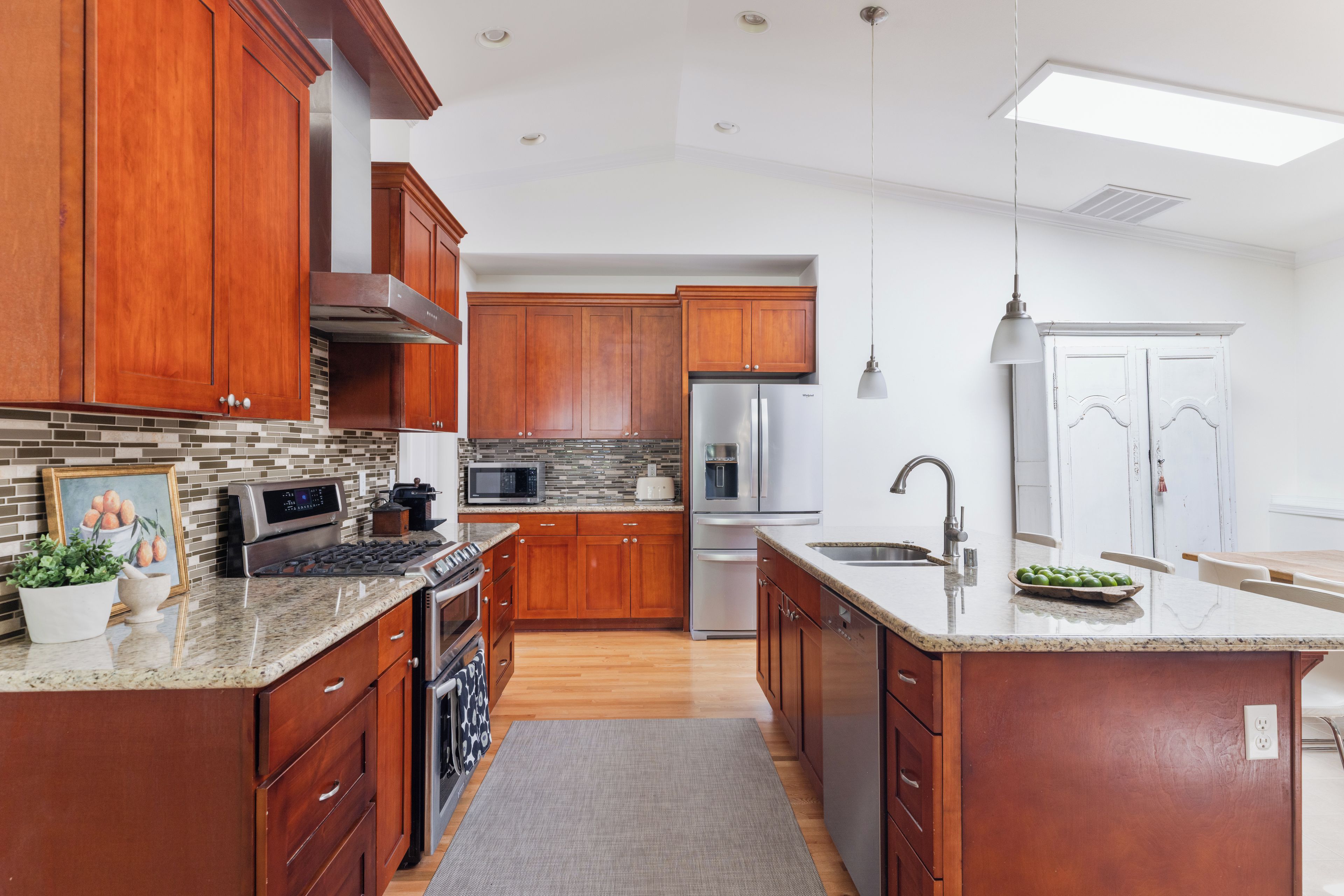A modern kitchen with wooden cabinets, stainless steel appliances, and a large island.