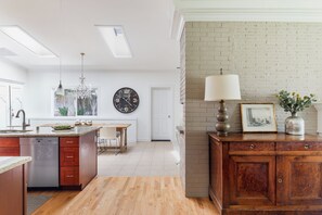 Eine moderne Küche mit Kochinsel, Essbereich und Wohnbereich mit Backsteinwand und Kamin.