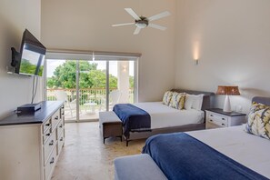 A hotel room with a balcony, a bed, a desk, a TV, and a ceiling fan. - Hacienda A57 - 4BR golf front villa close to beach club (Punta Cana)