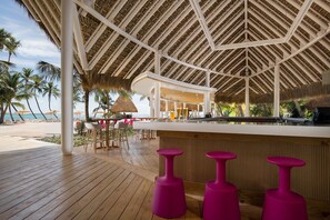A beachside bar area with a wooden deck, thatched roof, and a view of the ocean. - Hacienda A57 - 4BR golf front villa close to beach club (Punta Cana)