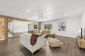 A spacious living room with a sectional sofa, a coffee table, and a television on a wooden stand. - Quiet 4BR Near Lake Somerville | Boat Parking (Somerville)