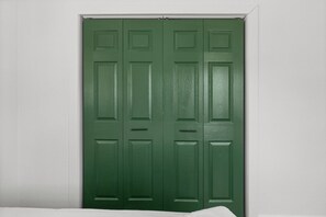 A closed green door with a white frame, set against a white wall. - Lakebound House: Ping Pong & Starlink WiFi Near (Somerville)
