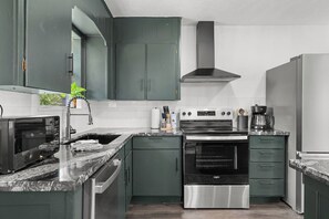 A kitchen with a built-in oven, microwave, and a coffee maker on the countertop. - Lakebound House: Ping Pong & Starlink WiFi Near (Somerville)