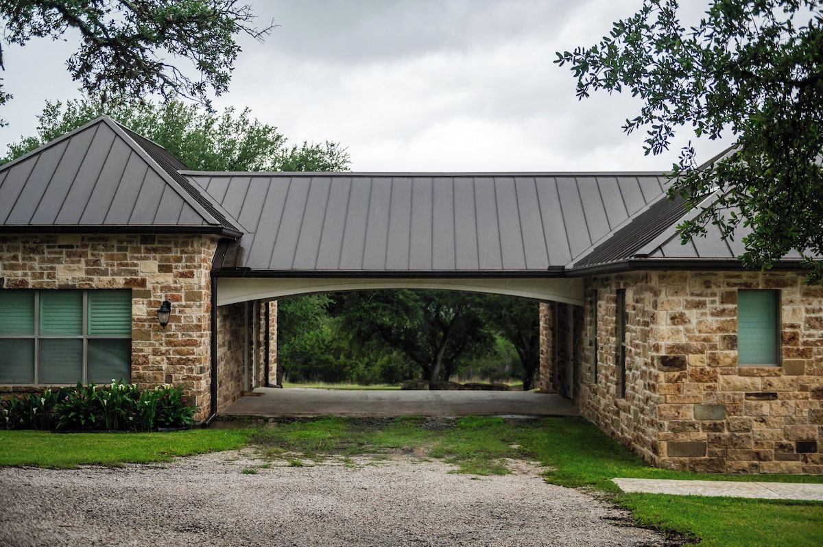 A stone building with a covered entrance and a gravel driveway.