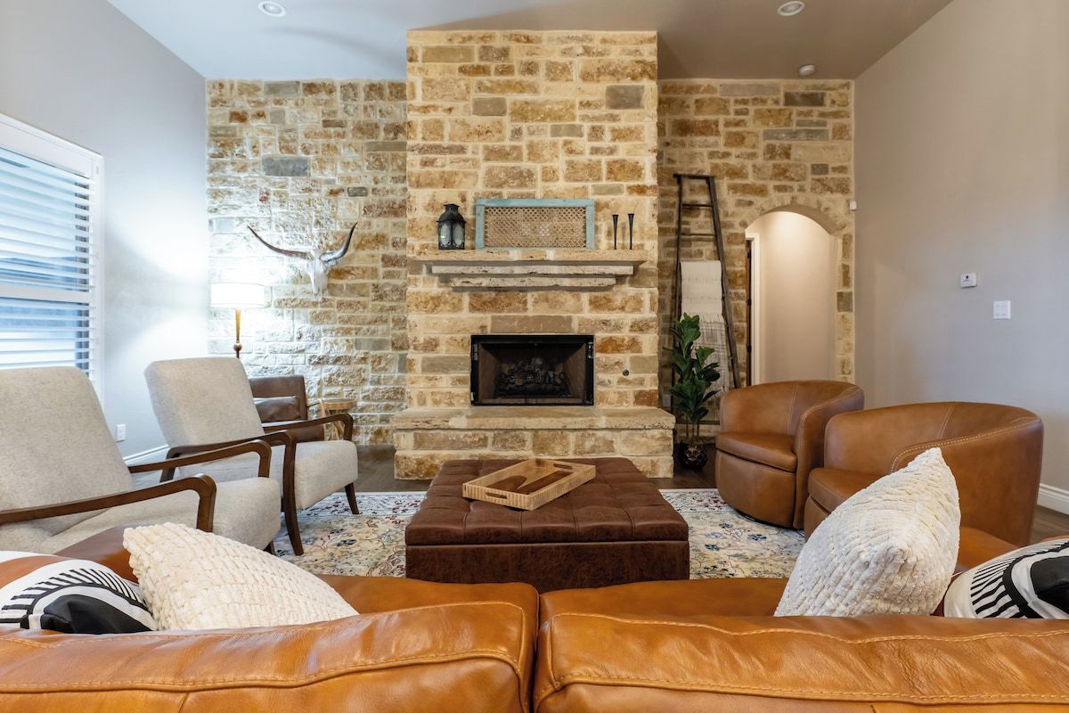 Una sala de estar con chimenea de piedra, sofás de cuero y una escalera en la pared.