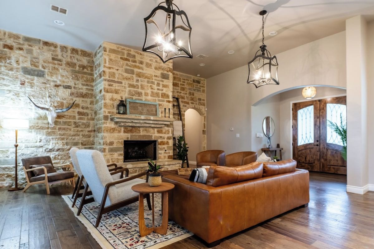 Una sala de estar con pared de piedra, sofá de cuero y chimenea.