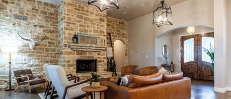 Una sala de estar con pared de piedra, sofá de cuero y chimenea.
