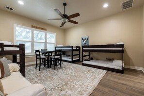 A room with bunk beds, a ceiling fan, a desk with chairs, and a rug. - Hill Country Reunion & Event Estate | Sleeps 28 (Fredericksburg)