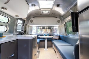 Ein kompaktes Wohnmobil-Interieur mit Küchenzeile, Essbereich und einer Sitzgelegenheit.