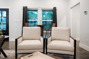 Ein Wohnzimmer mit zwei Sesseln, einem Couchtisch und einem Esstisch mit Stühlen.