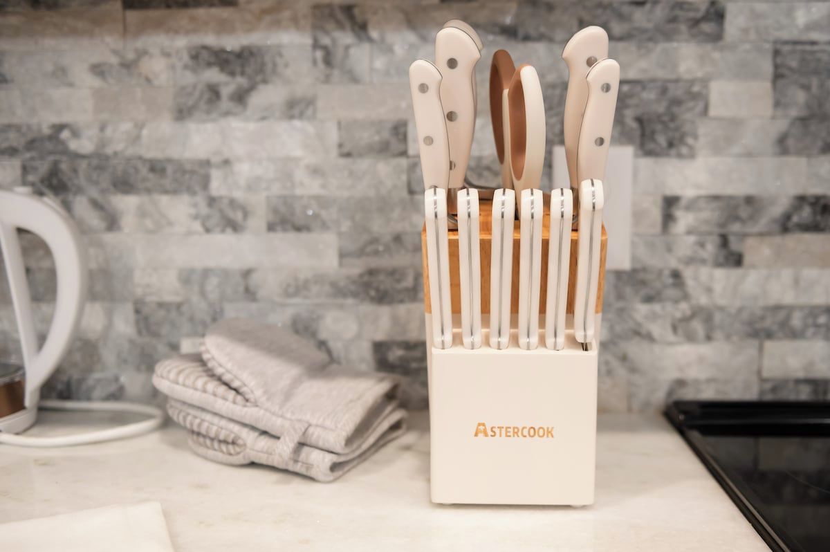Un porte-ustensiles de cuisine contenant des couteaux et une serviette en tissu pliée, posé sur un plan de travail.