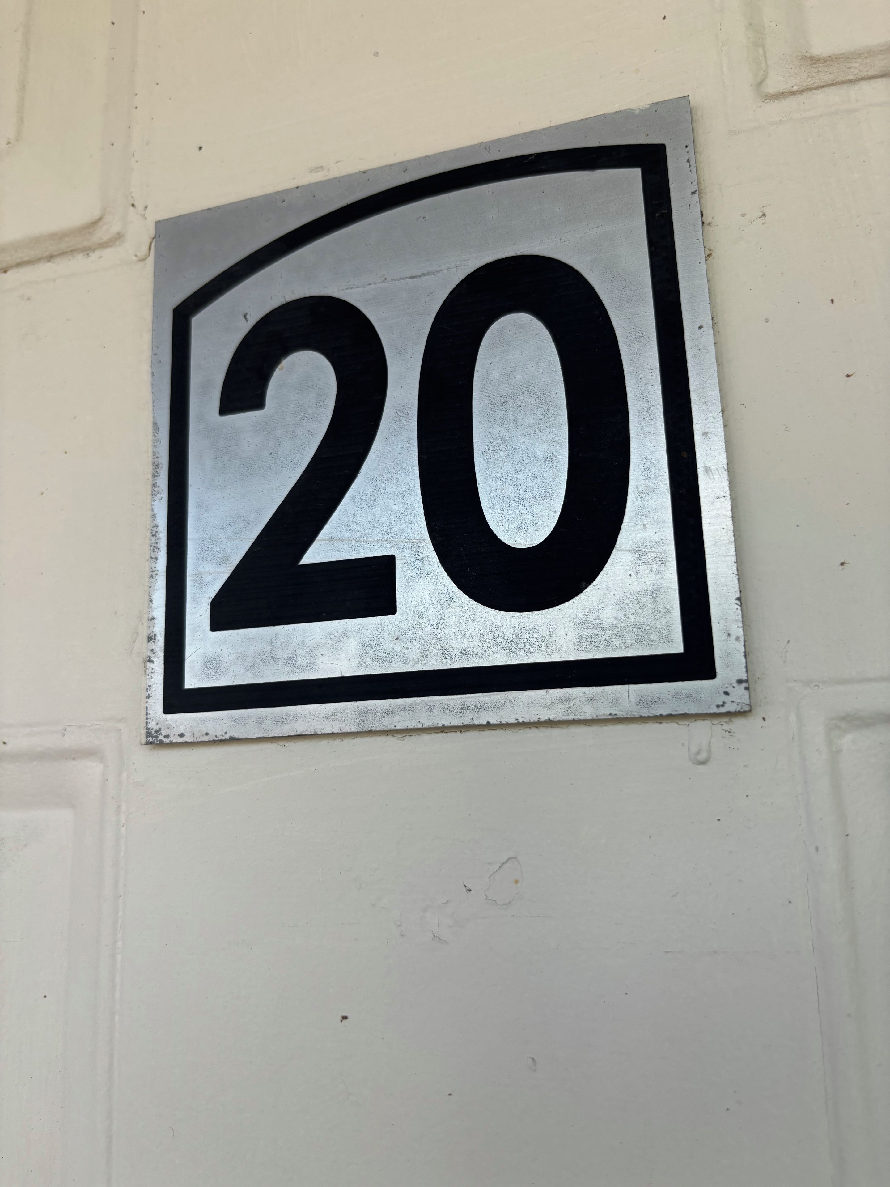 Ein Metallschild mit der Nummer 20 an einer Wand.