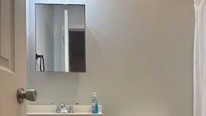 Een badkamer met een wit toilet, een wastafel met spiegel erboven en een douchegordijn.