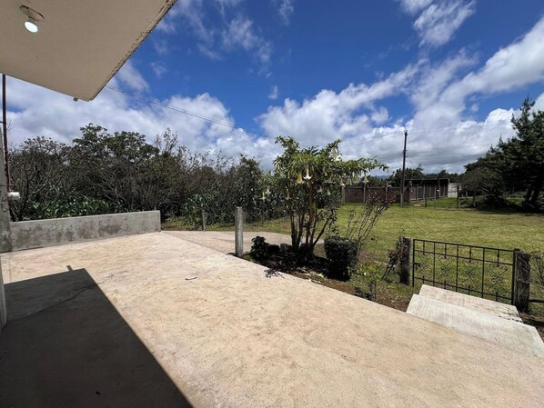 A concrete patio with a view of a grassy yard and trees.
