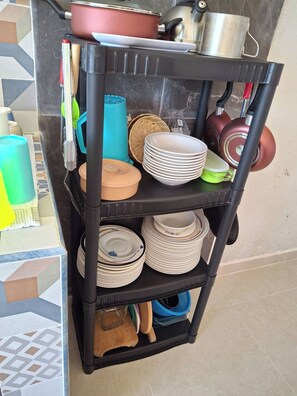 A kitchen shelf with various kitchenware and utensils.