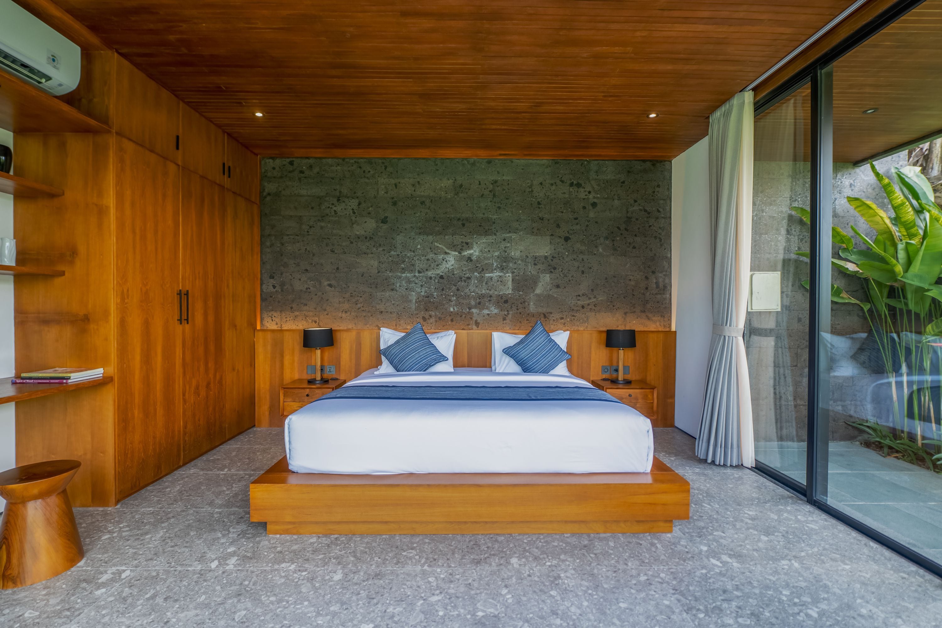 Quarto moderno com uma cama grande, guarda-roupa de madeira e parede de pedra.