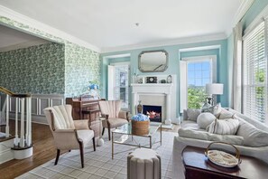 A living room with a fireplace, a piano, and a staircase. - The Pearl Retreat (Nashville)